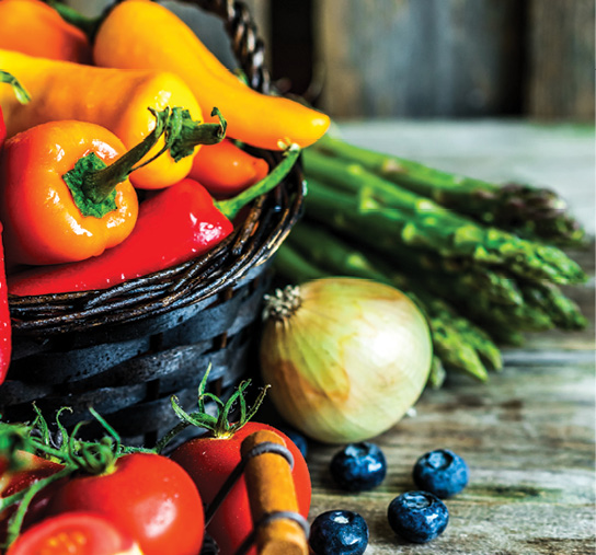 basket full of colorful vegetables sitting on a wood table