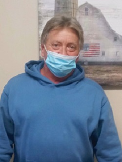 middle aged man wearing light blue hoodie and blue mask standing for photo