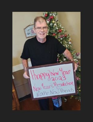 Franklin-Simpson Featured Resident Mr. B pictured next to Christmas Tree with a Happy New Year sign